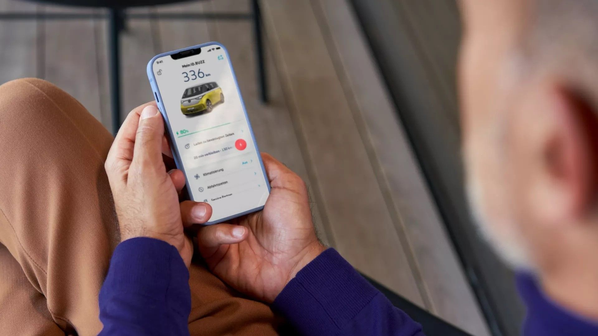 Ein Mann kontrolliert den Ladezustand eines VW ID. Buzz über die We Connect App