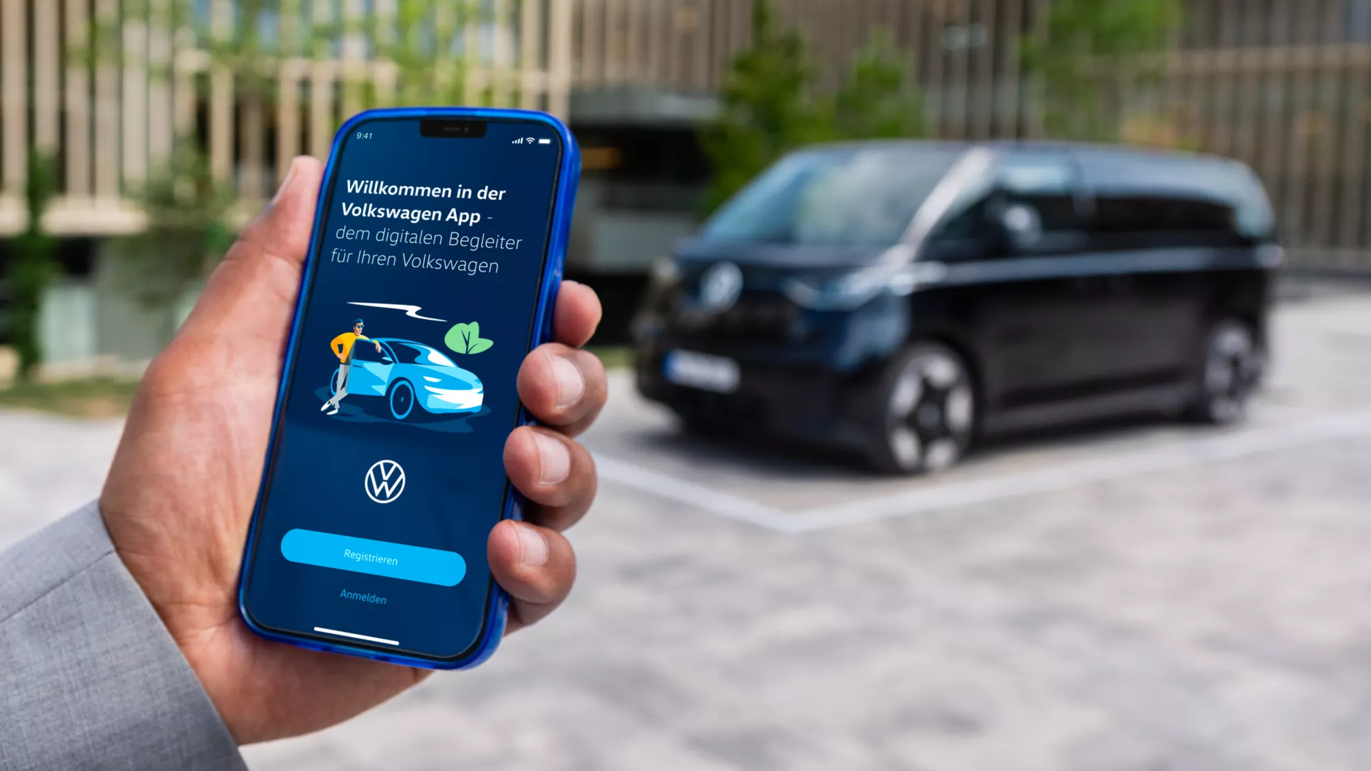 Mann meldet sich bei der Volkswagen App an, schwarzer ID. Buzz im Hintergrund